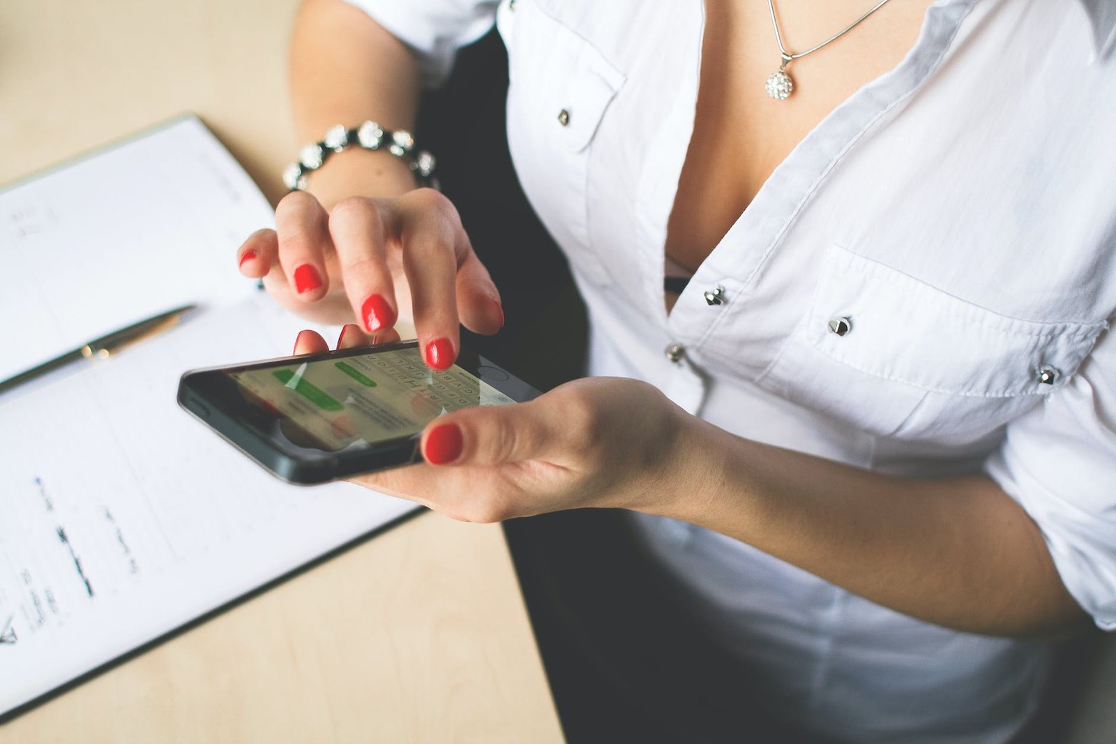 woman in white button up top and holding black android smartphone